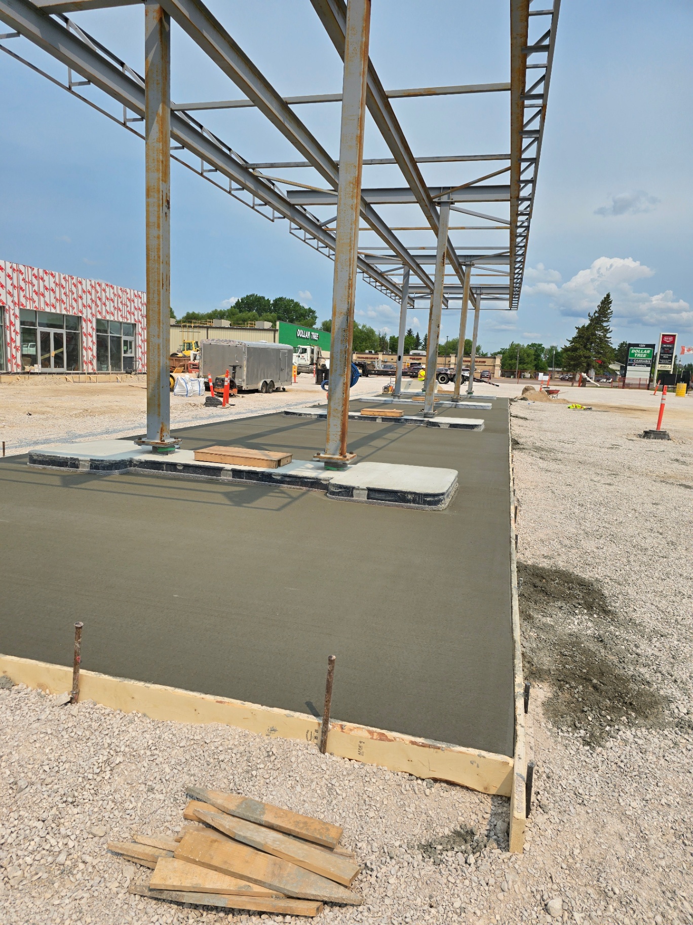 Freshly poured commercial concrete pad under steel canopy structure for a new retail building in Manitoba