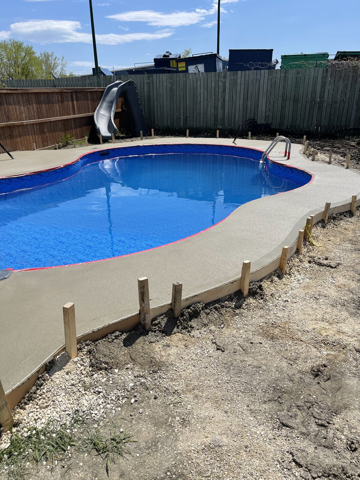 Curved poured concrete pool deck around an in-ground pool in Winnipeg